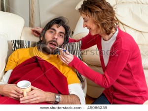 stock-photo-an-ill-husband-is-having-his-temperature-checked-by-his-wife-he-s-wrapped-up-on-the-couch-and-she-45086239